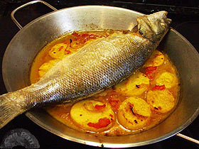 Lubina al horno con patatas, cebolla y tomate
